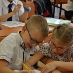 Two diverse elementary school children classmates studying together at desk