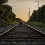 person in black jacket walking on train rail during daytime